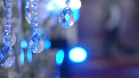 Pequeños-Cristales-En-Forma-De-Perla-Que-Se-Balancean-De-La-Luz-Con-Fondo-De-Luz-Azul