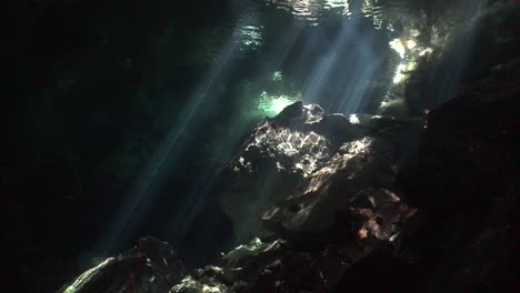 Sun-rays-shining-through-water-surface-onto-rock-formation-in-Cenote-Chikin-Ha-cave-system-Yucatan-Mexico