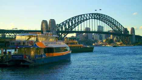 Ocean-Wave,-Manly-Fast-Ferry-Boat-At-The-Terminal-With-Sydney-Harbour-Bridge-In-The-Background-In-NSW,-Australia