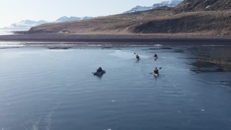 Adventure-kayakers-paddling-towards-volcanic-beach-in-Iceland-fjord,-Holmanes