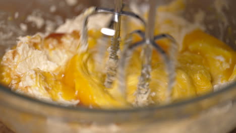Adding-egg-yokes-to-the-batter-then-stirring-the-dough-with-a-hand-mixer---close-up-slow-motion