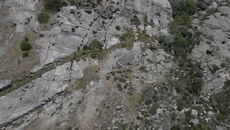 Drone-follows-a-herd-of-goats-over-the-rocky-surface-at-Lagoa-Comprida