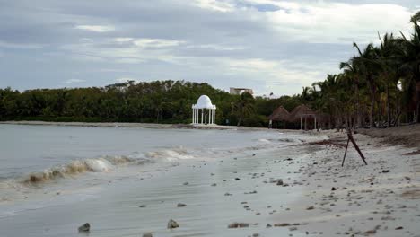 A-beautiful-gazebo-on-the-sand-next-to-the-beautiful-coastline-of-Playa-del-Carmen-in-Riviera-Maya,-Mexico-near-Cancun-and-Tulum-on-a-windy-overcast-evening-at-a-tropical-resort
