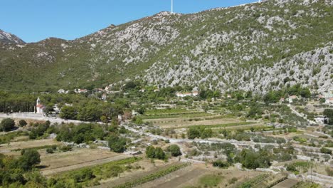 An-aerial-liftoff-over-sun-scorched-landscape-in-Dalmatian-karst,-village-of-Seoca,-Omis,-Croatia