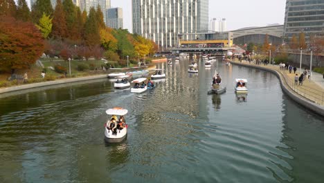 Incheon-Songdo-Central-Park---People-ride-paddle-boats-on-lake-and-walking-by-in-Colorful-Autumn,-South-Korea