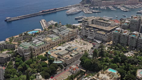 Monaco-Aerial-v15-birds-eye-view-drone-flying-around-monte-carlo-casino-square,-capturing-downtown-cityscape-and-coastal-deepwater-harbor---July-2021