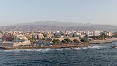 Apartment-buildings-district-on-sea-coastline-in-Chania-city,-Crete,-aerial-drone-view-with-vertigo-effect