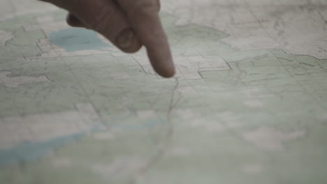 Closeup-Showing-An-Old-Man's-Finger-Tracing-And-Pointing-On-A-Paper-Map