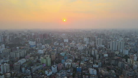 Aerial-top-view-of-populated-city-at-sunrise-with-dense-buildings---establishing-drone-descending-shot
