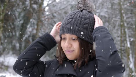 Beautiful-female-putting-on-winter-hat-during-heavy-snowfall
