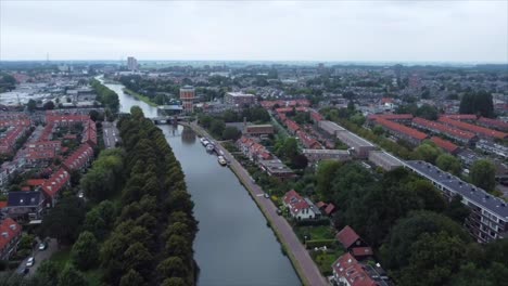 Luftaufnahme-Eines-Bootes-Auf-Einem-Fluss,-Der-Durch-Eine-Stadt-In-Den-Niederlanden-Fließt