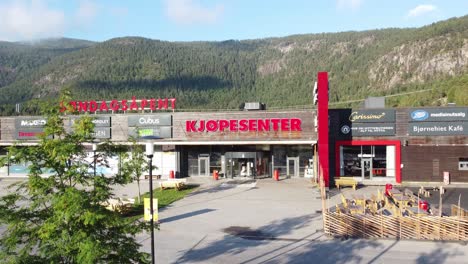 Bjorneparken-Einkaufszentrum-In-Flaa-Norwegen---Sonniger-Tag-Aufsteigende-Luft-Hinter-Baum---Aufschlussreiches-äußeres-Des-Einkaufszentrums-Mit-üppigem-Berghintergrund