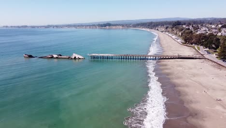 Schäumende-Meereswellen-Treffen-Auf-Die-Sandige-Kalifornische-Küste-Mit-Pier-Und-Versunkenem-Frachtschiff-SS-Palo-Alto