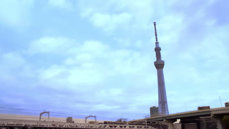 Tokio-Skytree,-Asakusa,-Tokio,-Japan-Ca.-April-2020:-Lastwagen-Und-Autos,-Die-Auf-Einer-Brücke-Fahren,-überqueren-Die-Gleise,-Der-Zug-Fährt-Langsam