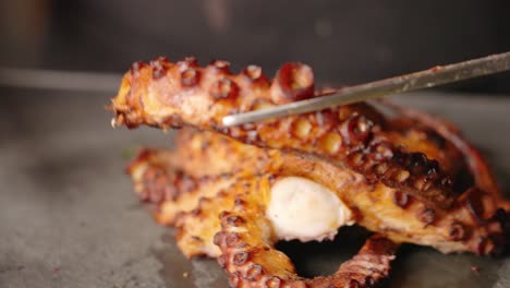 Golden-brown-crispy-perfectly-sealed-octopus,-chef-transferring-cut-tentacle-to-the-side-before-plating
