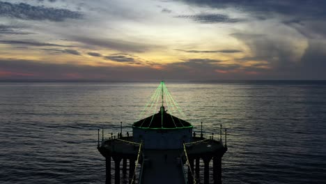 Pier-In-Manhattan-Beach-California-USA-Illuminated-With-Lights-During-Sunset---aerial-pullback