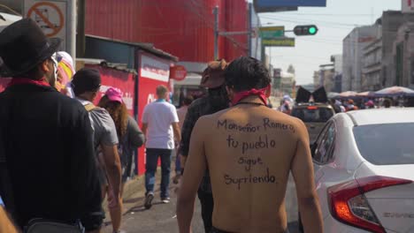 Man-walks-shirtless-with-a-message-written-on-his-back-during-a-peaceful-protest-against-the-current-president-Nayib-Bukele---Slow-Motion