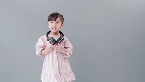 Girl-with-dress-dancing-and-spinning-with-headphones-in-front-of-gray-background