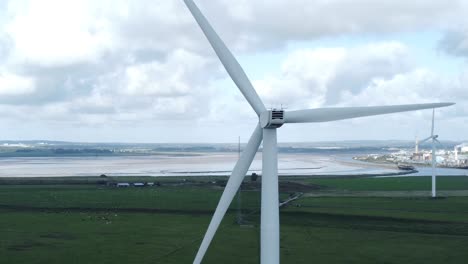 Alternative-green-energy-wind-farm-turbines-spinning-in-Frodsham-Cheshire-fields-aerial-view-slow-left-orbit
