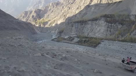 Aerial-Over-Gravel-Dirt-Landscape-With-4x4-Truck-Parked-On-Cliff-Edge-In-Skardu