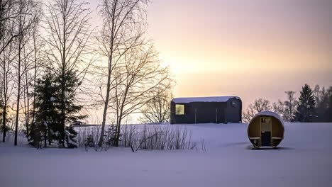 Time-lapse-of-flying-stars-during-sunset-at-sky-in-white-winter-landscape-with-barrel-sauna-and-wooden-hut
