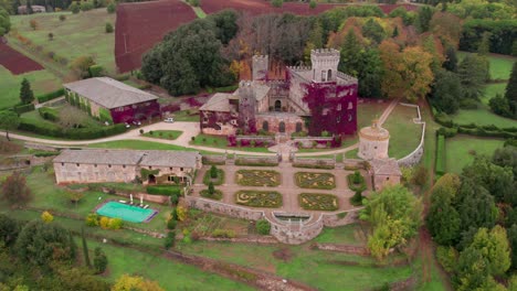 Luxury-medieval-stone-castle-with-lush-gardens-in-rural-woodland,-aerial