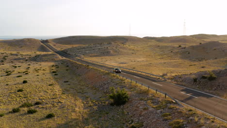 Car-Traveling-On-The-Road-Amidst-The-Scenic-Landscape-AT-Dusk-In-Pag-Island,-Croatia