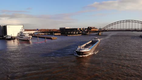 Aerial-View-Of-Fenny-II-Inland-Container-Vessel-Along-River-Noord-With-Brug-Over-De-Noord-In-Background