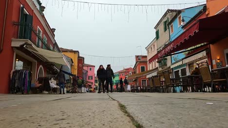 Low-angle-ground-surface-first-person-pov-of-people-walking-in-Burano-downtown-and-colorful-houses