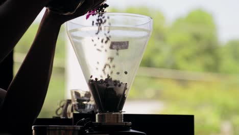 Filling-plastic-container-of-the-machine-with-freshly-roasted-coffee-beans
