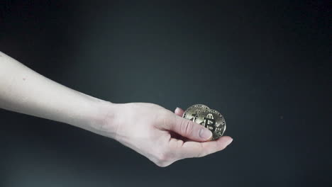 Mano-Sosteniendo-Monedas-De-Criptomoneda-Bitcoin-Brillante,-Fondo-Negro
