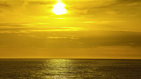 View-of-sun-rising-from-behind-the-white-clouds-in-timelapse-over-the-sea-water-along-the-coast-in-Via-Molino,-Italy-at-dawn