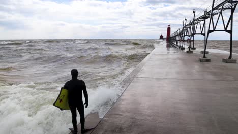 Surfer-diving-into-Lake-Michigan-off-the-pier-in-Grand-Haven,-Michigan