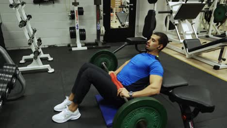Strong-man-performing-hip-thrusts-inside-a-gym-full-of-equipment