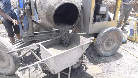 Nahaufnahme-Eines-Diesel-Betonmischers,-Der-Nassen-Zement-In-Die-Schubkarre-Auf-Der-Baustelle-In-Indien-Gießt