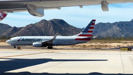 Ein-American-Airlines-Jet-Auf-Dem-Asphalt-Bereitet-Sich-Auf-Den-Abflug-Mit-Berglandschaft-Im-Hintergrund-Vor