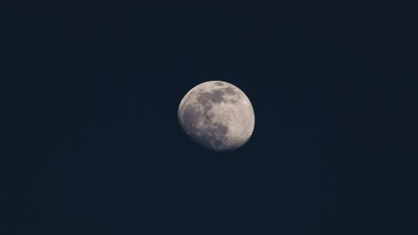 Full-moon-slowly-moving-across-a-dark-blue-sky-at-night,-telescope-video