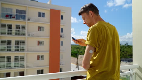 Male-Traveller-Checks-His-Blood-Glucose-Levels-On-Left-Arm-With-Freestyle-Libre-2-Sensor-By-Hotel-Balcony