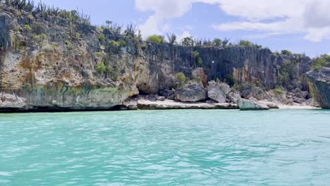 Pov-shot-of-boat-showing-CABO-ROJO-PEDERNALES-cliffs-and-splashing-water-during-sunny-day