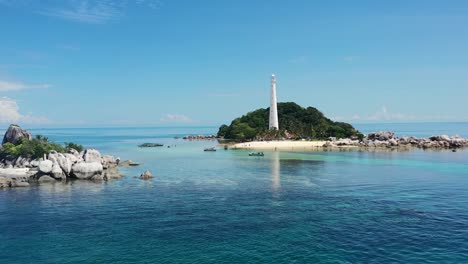 aerial-drone-of-Kepayang-Island-in-Belitung-Indonesia-with-a-large-white-lighthouse-surrounded-by-forest-on-a-tropical-sunny-day