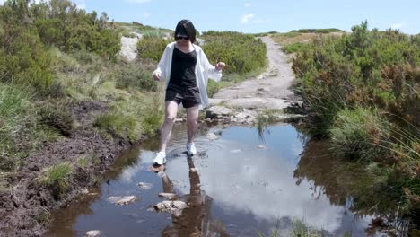 Woman-balances-on-rocks-in-a-puddle-in-the-Serra-da-Estrela
