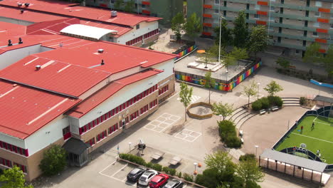 Schönes-Schulgebäude-Und-Hof-In-Einem-Vorort-Von-Stockholm-In-Der-Nähe-Von-Lebenden-Gebäuden,-Luftdrohne-Rückansicht