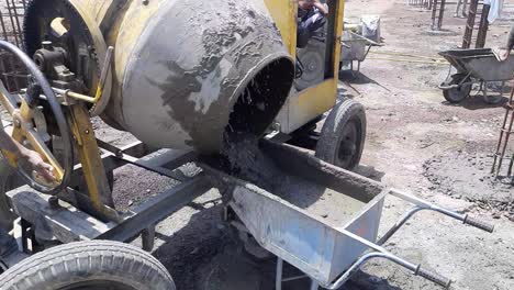 Concrete-mixer-pouring-wet-cement-into-the-wheelbarrow