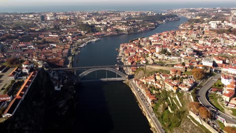 Panoramic-aerial-view-of-Porto-city-center-bridge-Douro-river-during-a-sunny-day,-drone-fly-above-old-town