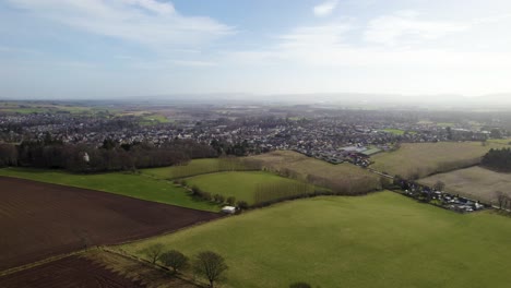 Aerial-Drone-flying-over-ploughed-and-grassy-fields-towards-Blairgowrie-and-Rattray,-Scottish-Farming-Town-in-Perthshire
