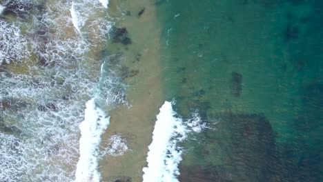 Top-Down-Waves-at-a-beautiful-ocean-coast---drone-shot-rocks-and-blue-green-waves