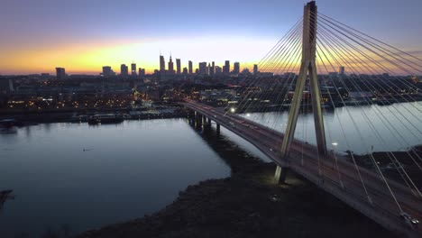 Bridge-and-city-of-Warsaw-illuminated-at-dusk-in-cinematic-aerial-view