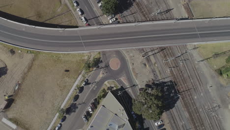 Black-car-driving-through-round-about-as-seen-from-static-aerial-perspective