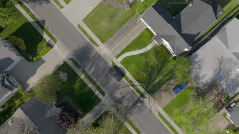 Aerial-straight-down-over-suburban-houses-and-street-with-a-bike-rider-on-the-street-as-camera-spins