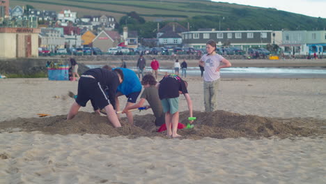 Group-Of-English-Children-Digging-Sand-At-Perranporth-Beach-In-Cornwall,-England---Static-Shot